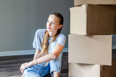 Side view of young woman sitting against wall