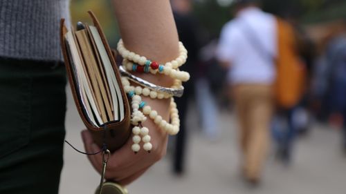 Close-up of person carrying religious book and rosary beads