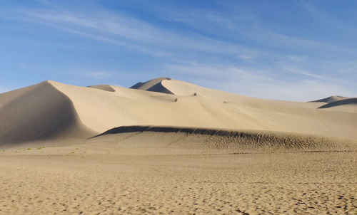 Sand dunes in desert against sky