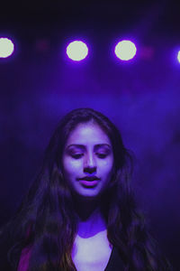 Young woman looking down against illuminated lights