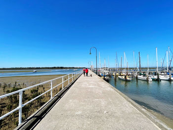 Pier over sea against clear blue sky