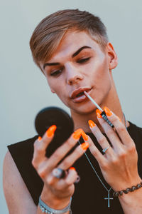 Young man applying make up against wall