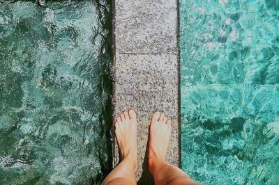 Low section of woman standing by swimming pool