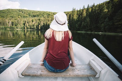 Rear view of woman sitting on boat sailing in lake