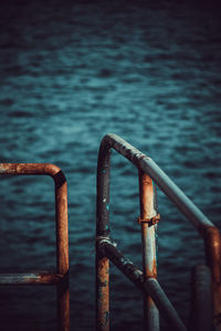 Close-up of rusty metal railing against sea