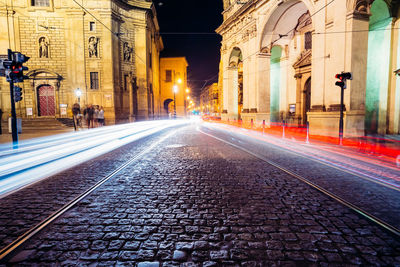 Light trails on street amidst buildings in city at night