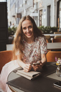 Portrait of a smiling young woman sitting on table