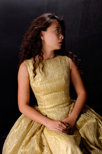 Woman in dress sitting against black background