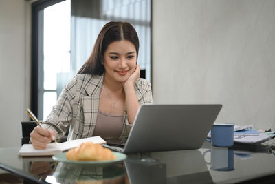 Young businesswoman using laptop at office