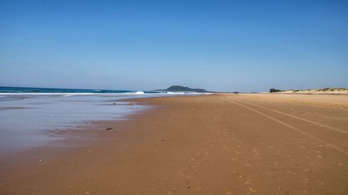 Scenic view of beach against clear blue sky