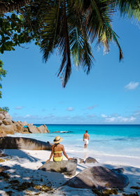 Low section of woman sitting on beach against sky