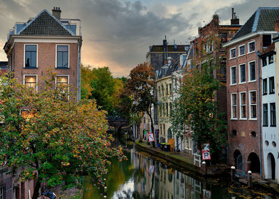 Canal amidst trees and buildings against sky