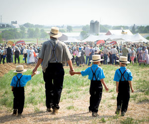 Rear view of father and sons walking on field at event