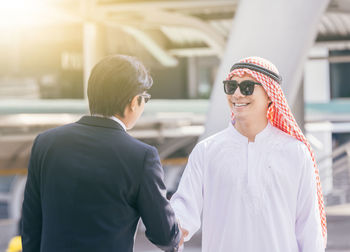 Business colleagues talking while standing in city during sunny day