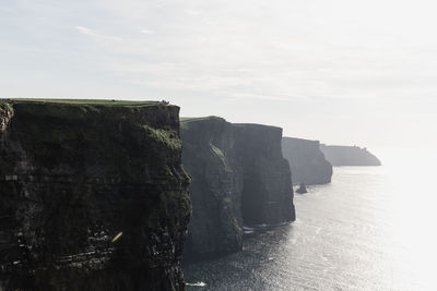 Scenic view of cliff by sea against sky