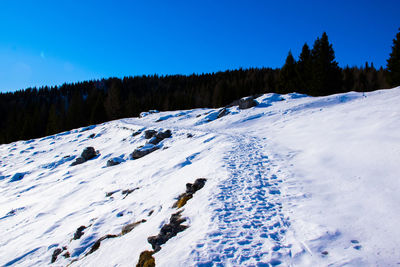 Scenic view of snow covered mountains against clear blue sky