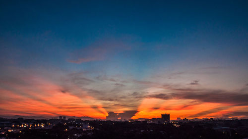 Silhouette cityscape against sky at night