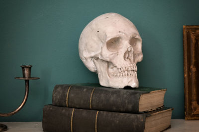 Close-up of skull on old books against wall