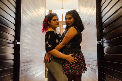 Portrait of smiling lesbian couple embracing in corridor