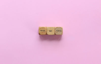 Close-up of text on wooden blocks against pink background