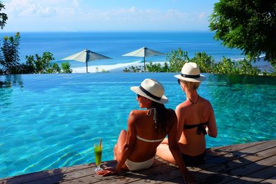 Rear view of woman looking at swimming pool against sea