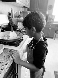 Side view of boy having food in kitchen