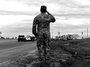 Rear view of man standing on road against sky