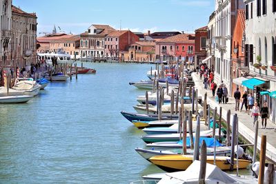 Boats moored at harbor against sky