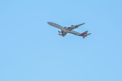 Low angle view of airplane against clear blue sky