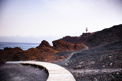 Lighthouse by sea against sky