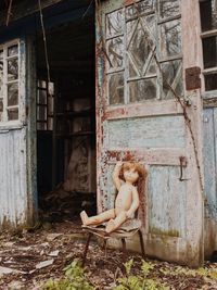 Side view of woman sitting in abandoned house