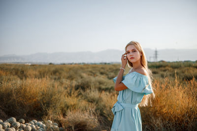 Portrait of teenage girl wearing dress standing on land against sky