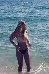 Young woman in bikini standing in shallow water at sea