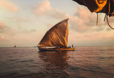 Boat sailing in sea against sky during sunset