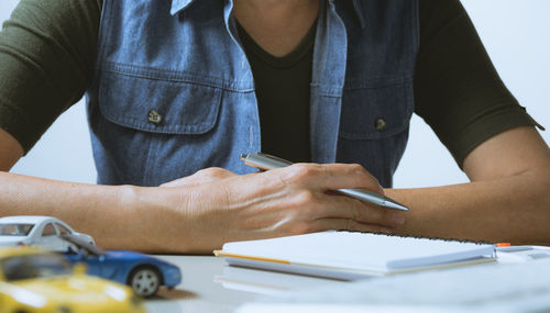 Midsection of man reading book on table