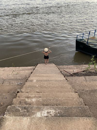 Rear view of man standing on pier over lake