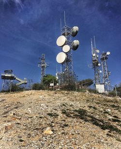 Low angle view of communication towers on field against sky