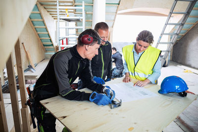 High angle view of construction workers discussing over blue prints at site