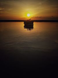 Silhouette boat in sea against sky during sunset