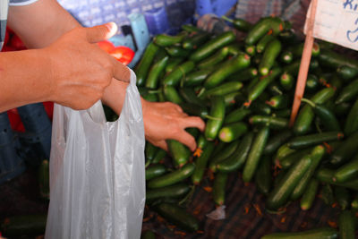 Midsection of woman holding vegetables at market stall
