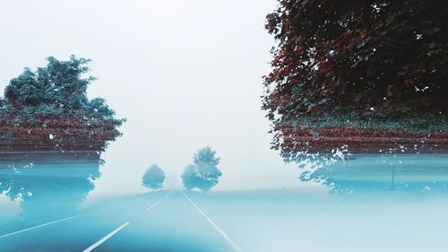 Road by trees against clear sky