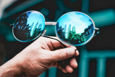 Close-up of man holding sunglasses in city