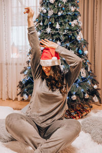 Beautiful young woman in santas hat decorating christmas tree. new year decoration. home interior.