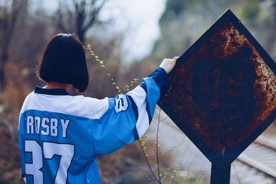 Rear view of woman standing by road sign