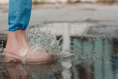 Low section of woman standing on wet shore