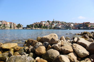 Scenic view of sea by buildings against clear blue sky