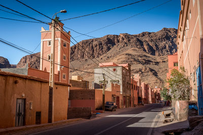 Road by buildings in city against sky