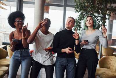 Group of multi ethnic people with alternative girl with green hair is standing together indoors.