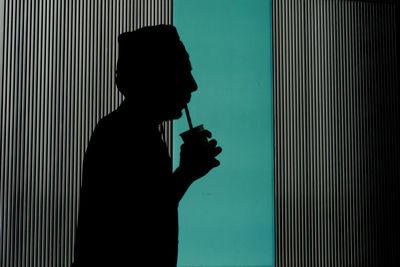 Silhouette of a man drinking through a straw 