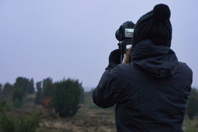 Rear view of man photographing against sky